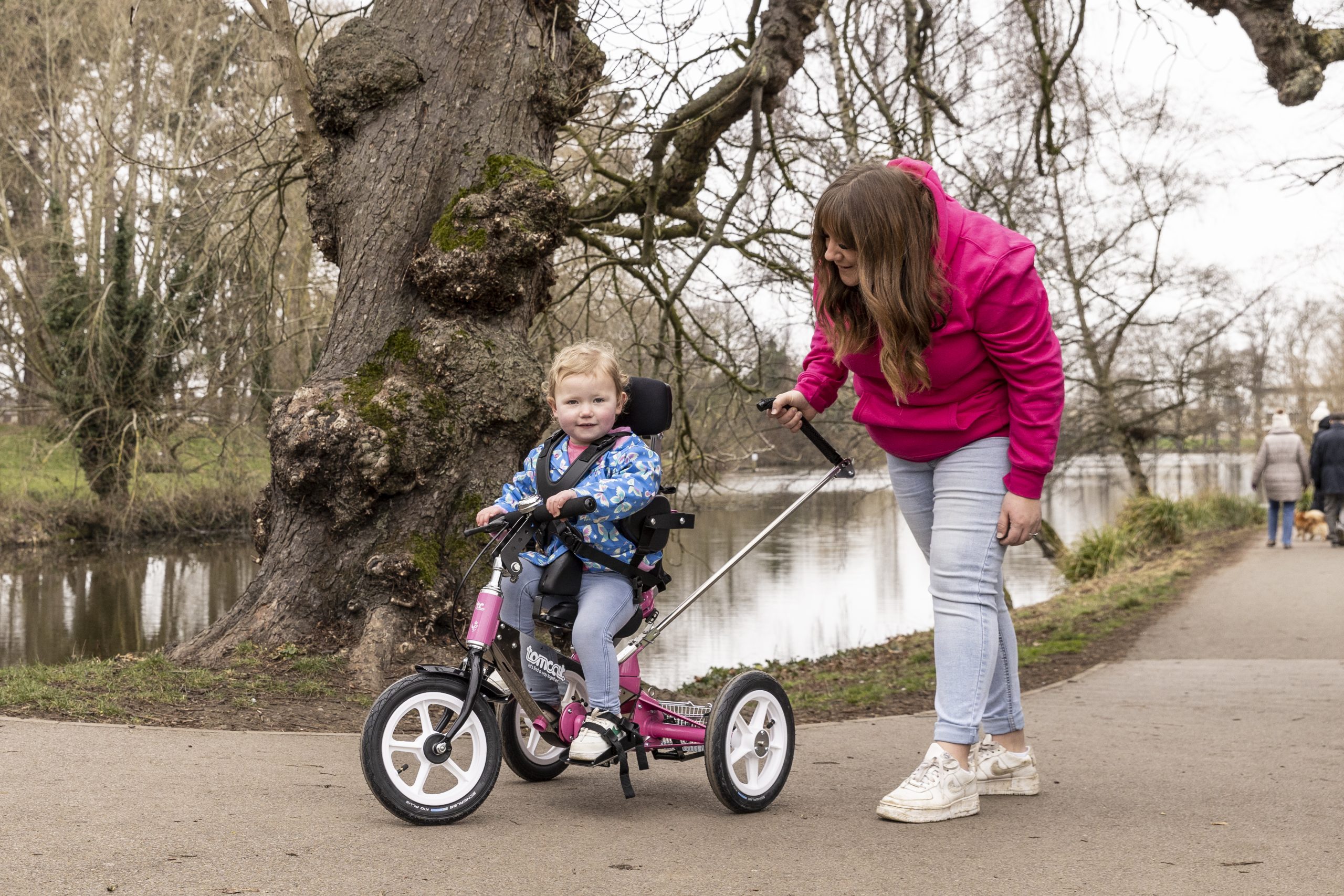 Amelia with her mum, riding the Tomcat Tiger through Pitville Park while smiling