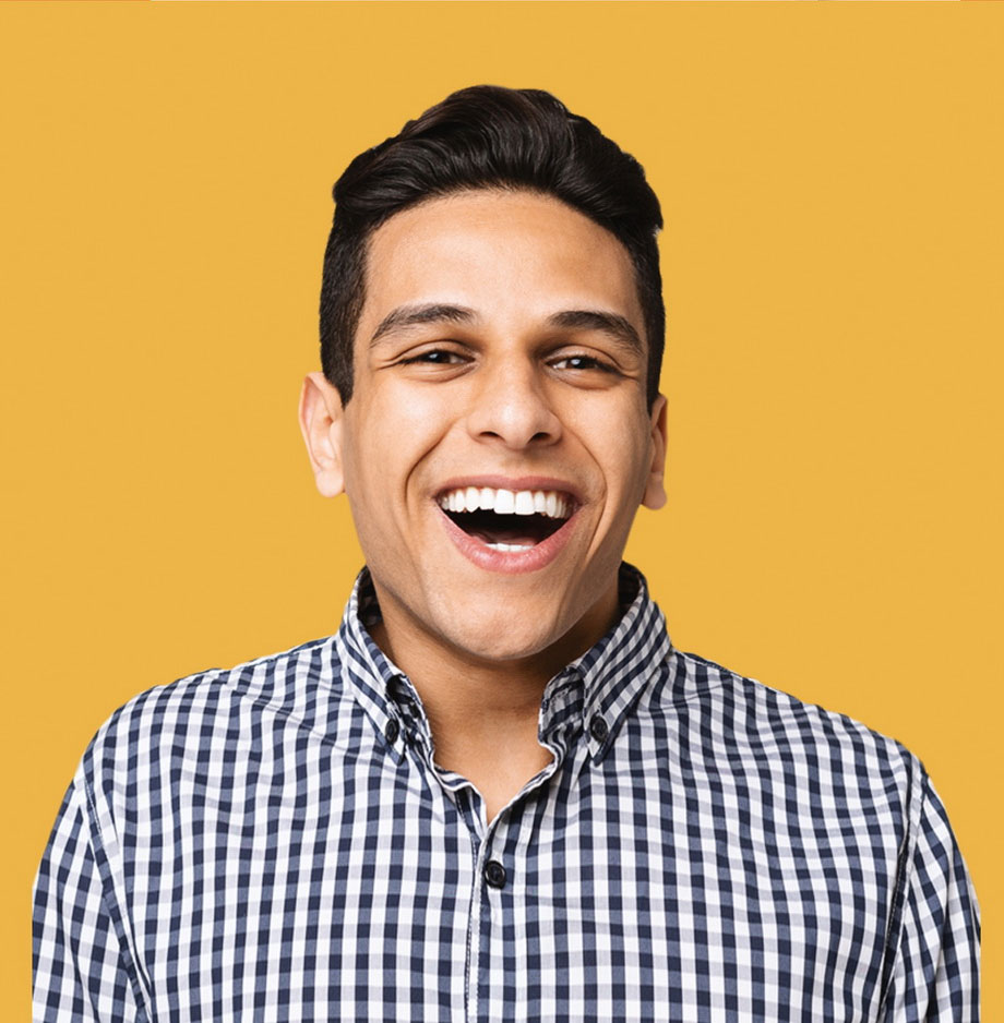 An image of a man in a chequered shirt, smiling at the camera, on a yellow background.